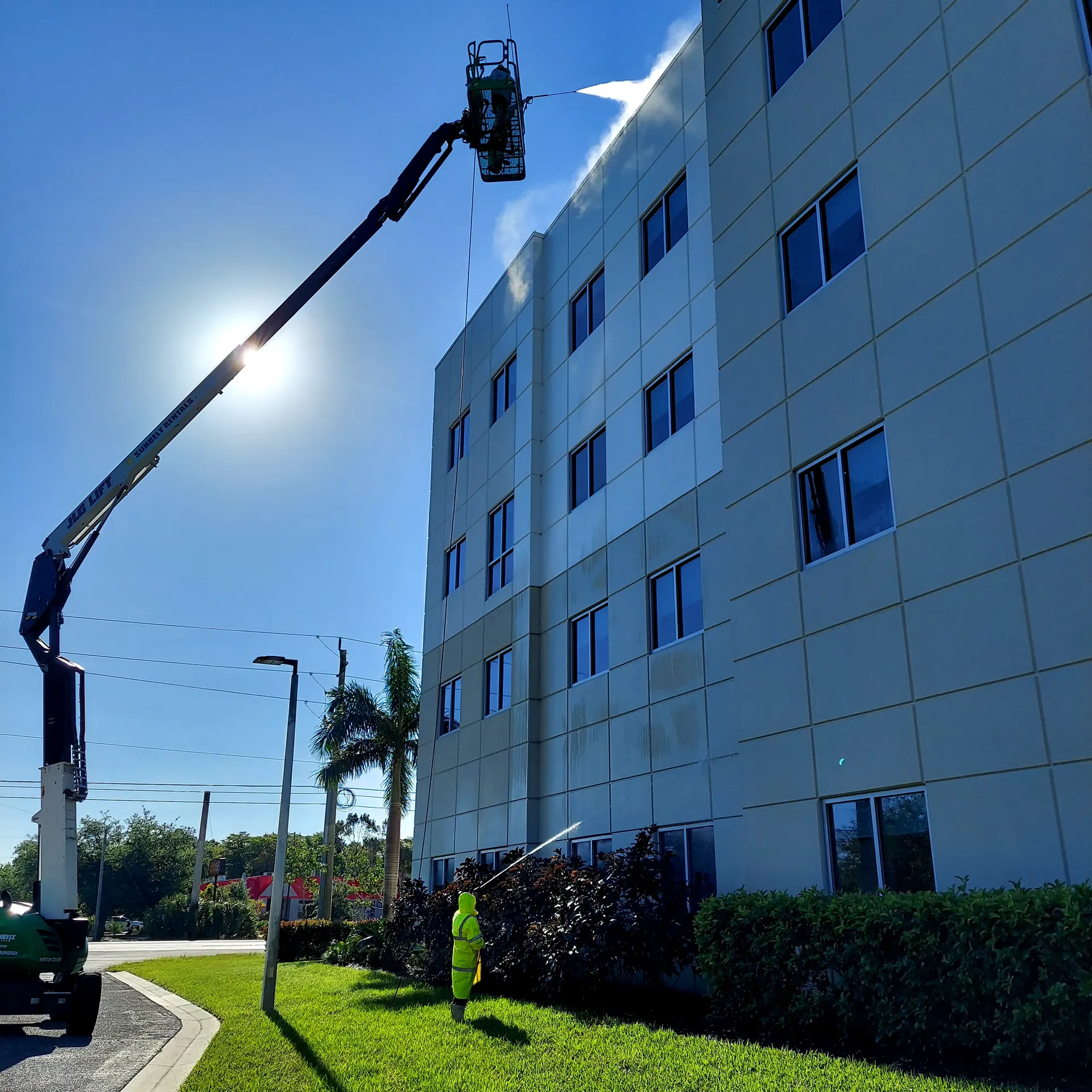 Blastmasters boom lift on commercial building with sun flare — SW Florida
