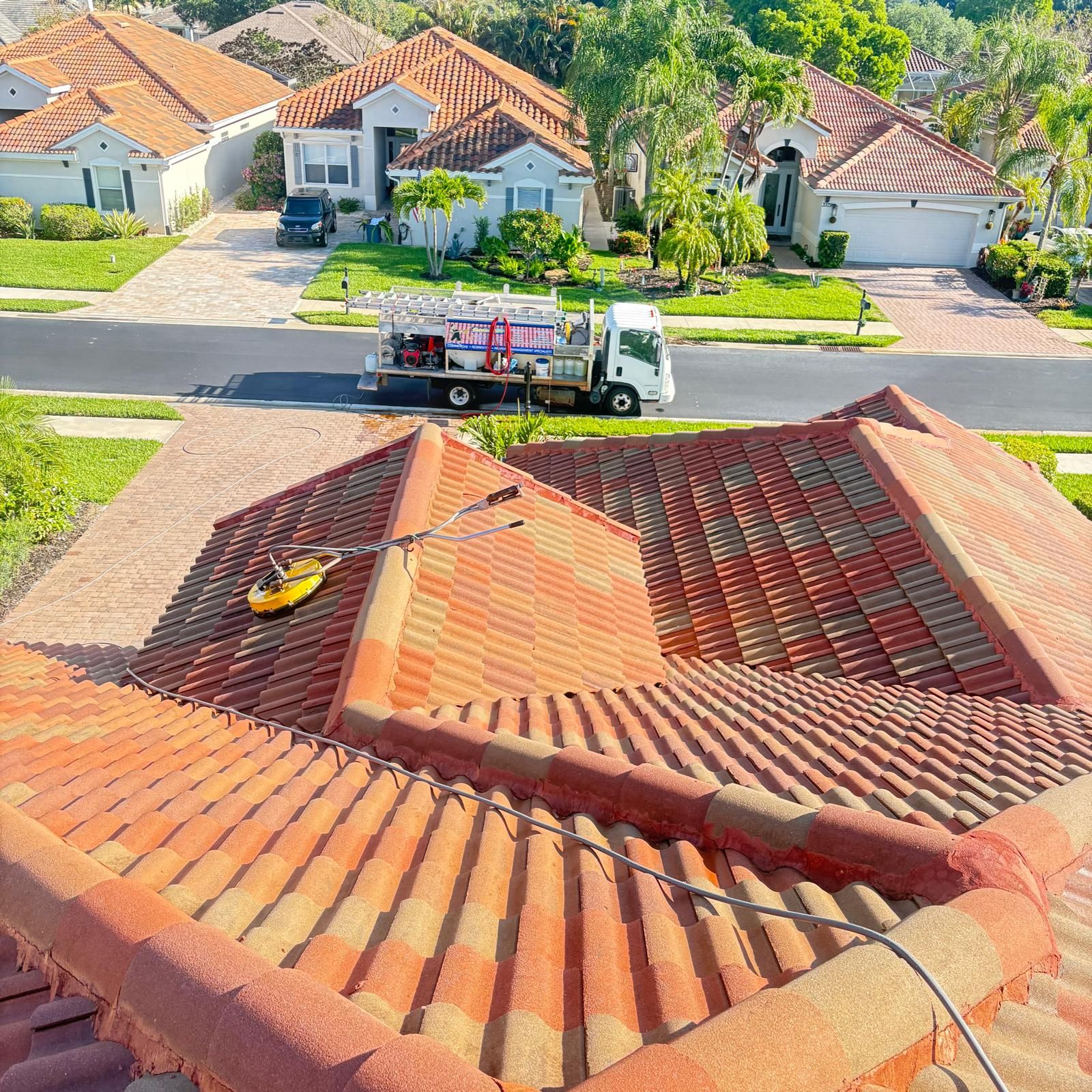 Blastmasters crew roof cleaning from above with truck visible — SW Florida